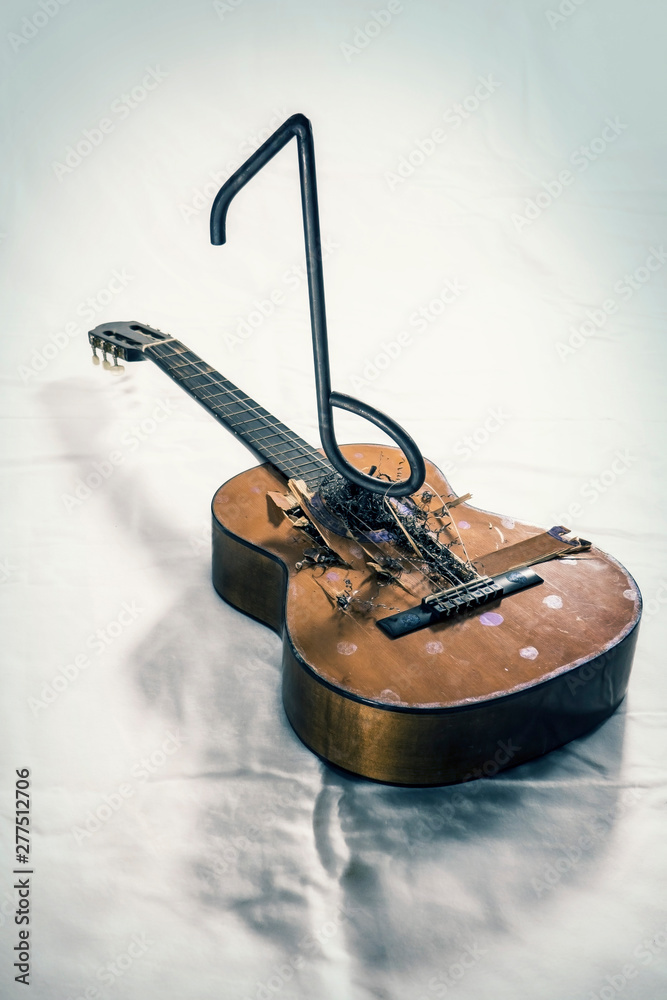 An acoustic guitar gets destroyed by a music note made out of iron