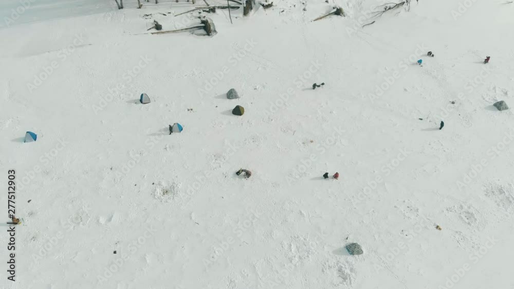 fishermen have rest fishing at holes on boundless frozen river surface with small camp of tiny tents bird eye view fishermen have rest fishing at holes on boundless frozen river surface with small camp of tiny tents bird eye view