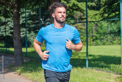 Handsome man running in park with trees in background