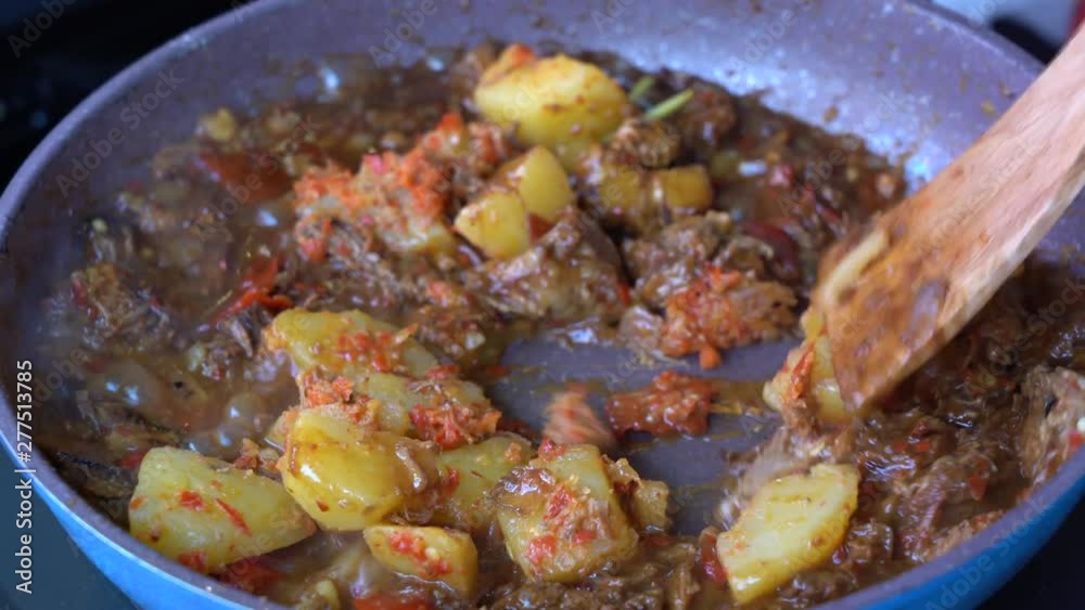 Frying pan with onion, lemongrass, red pepper and beef meat, close up. Indonesia. Sambal Goreng Ati Kentang, Indonesian cuisine, spicy beef meet and potatoes garnish with lemongrass leaf and red chili Frying pan with onion, lemongrass, red pepper and beef meat, close up. Indonesia. Sambal Goreng Ati Kentang, Indonesian cuisine, spicy beef meet and potatoes garnish with lemongrass leaf and red chili