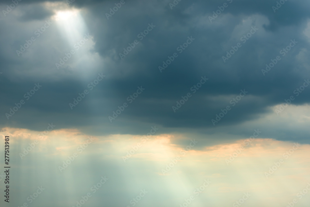 Sunset view of dramatic storm sky with dark clouds and bright sunbeams shining through them. Can be used as nature background