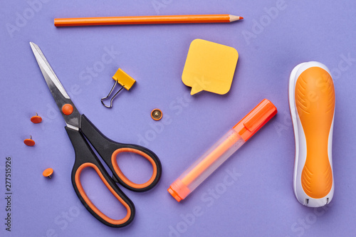 School supplies on purple background. Scissors, marker, stapler and sticky note on color background. Back to school.