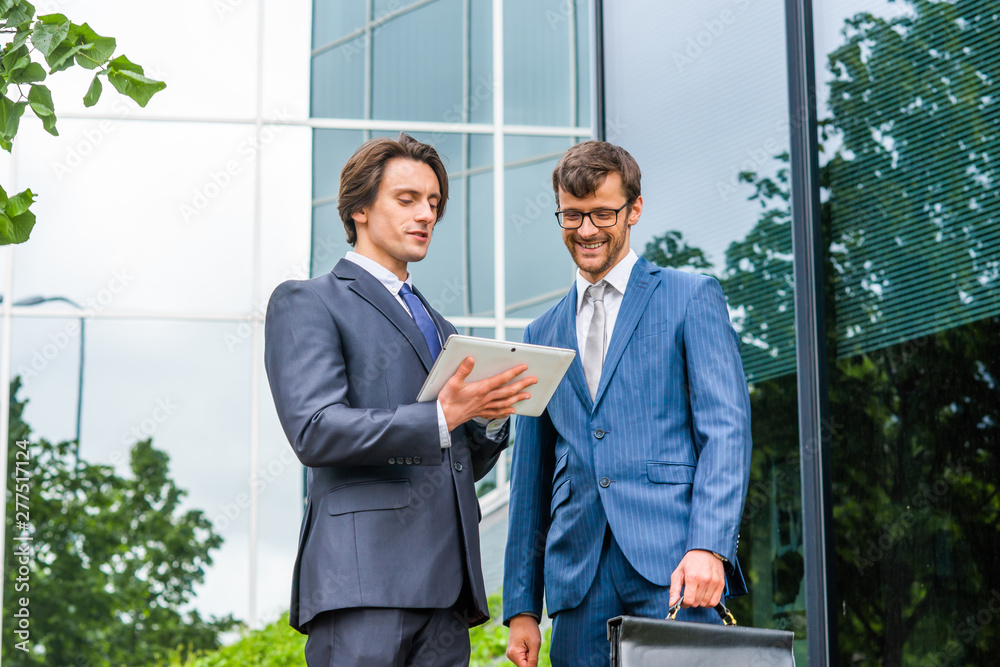 Confident business men talking in front of modern office building. Businessman and his colleague. Banking and financial market. Confident business men talking in front of modern office building. Businessman and his colleague. Banking and financial market.