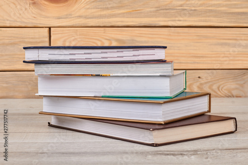 Stack of closed books on wooden background. Five books on wooden table. Education and knowledge concept.