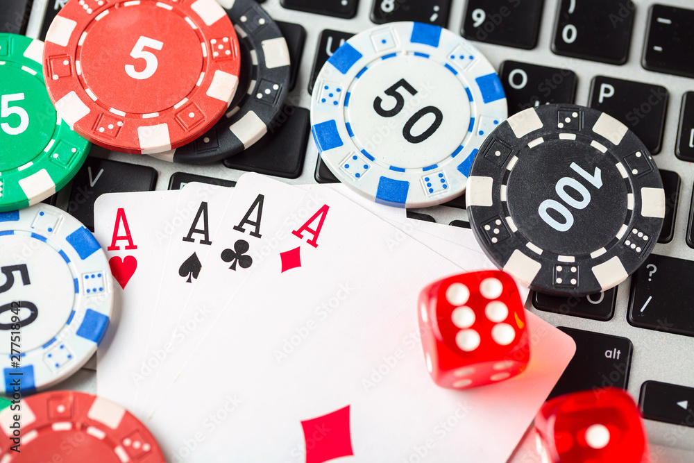 Online poker casino theme. Gambling chips with dice and aces playing cards on laptop. Online poker casino theme. Gambling chips with dice and aces playing cards on laptop.