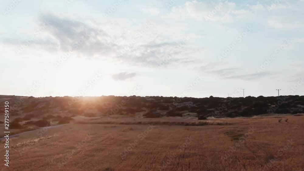 Beautiful rocky hills and wheat field in the countryside. Drone view of the rural farmland, road and hills on the island under sunset in summer. Beautiful rocky hills and wheat field in the countryside. Drone view of the rural farmland, road and hills on the island under sunset in summer.