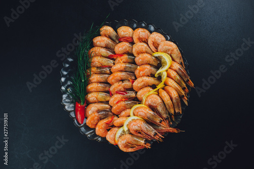 shrimps with lemon and black pepper on dark background top view