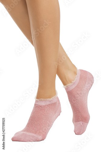 Cropped half-turn shot of lady's legs with smooth skin, wearing light pink shimmering low-cut socks, adorned with lace ruffles on the elastic band. The girl is making step against white background.