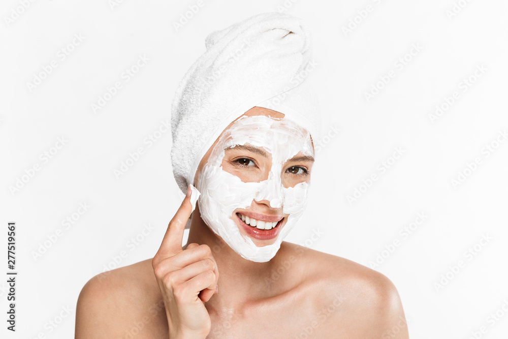 Image of gorgeous half-naked woman wrapped in towel applying facial cream and smiling at camera Image of gorgeous half-naked woman wrapped in towel applying facial cream and smiling at camera