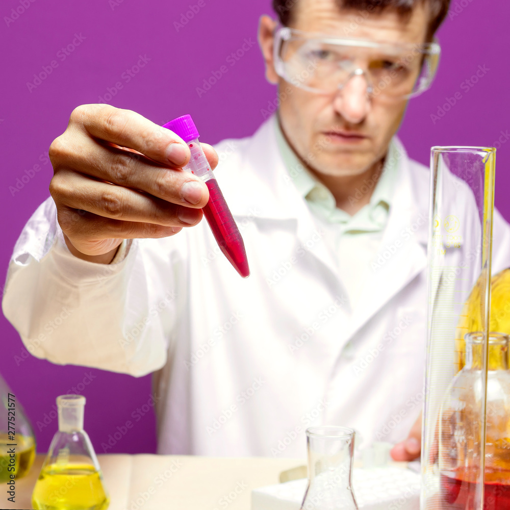 Lab technician looking at a flask with chemicals Lab technician looking at a flask with chemicals