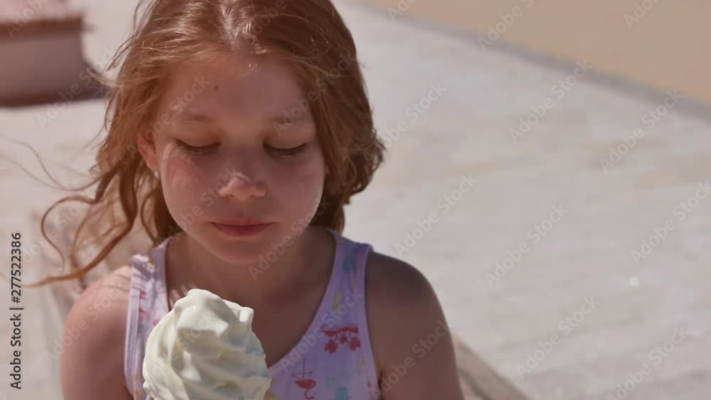 jolie fillette dégustant une crème glacée sur la plage ensoleillée