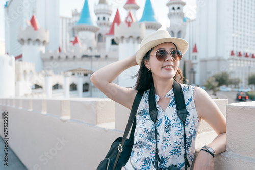 Photography smiling girl backpacker with camera visit famous and historic hotel and casino located on south end of Las Vegas strip