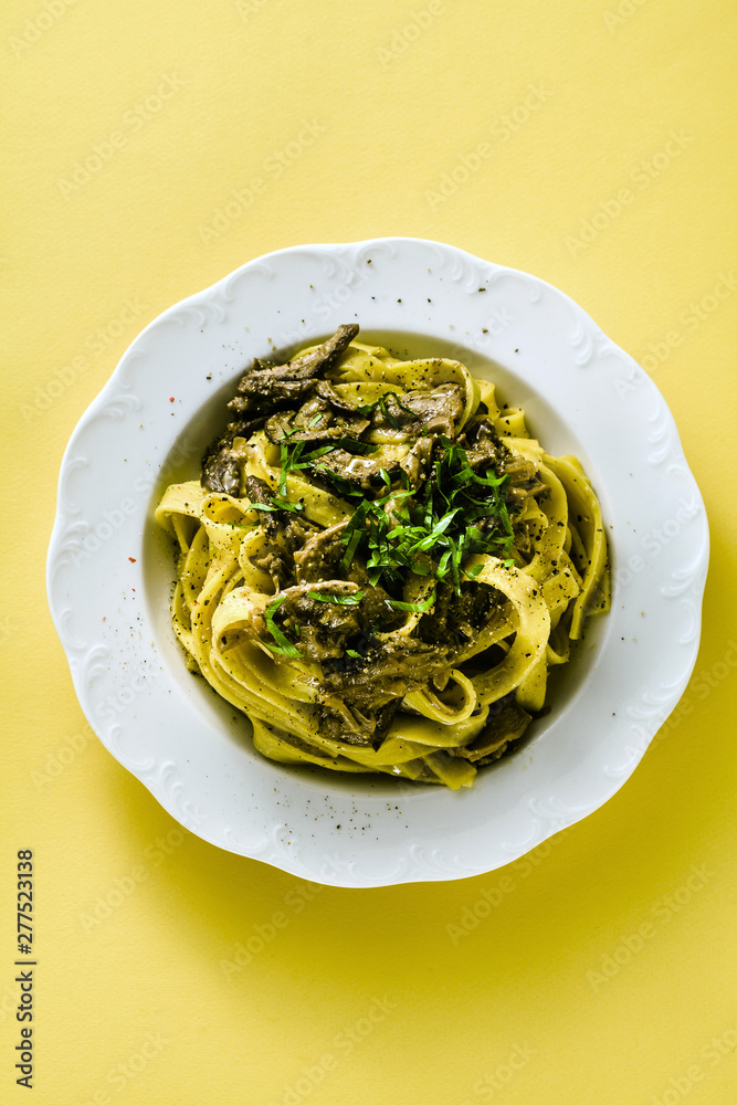 fresh italian pasta tagliatelle with porcini mushrooms in a plate on a white background