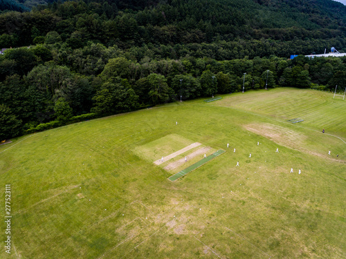 Aerial view of players, playing a game of Cricket on a Welsh Park Pitch in the summer