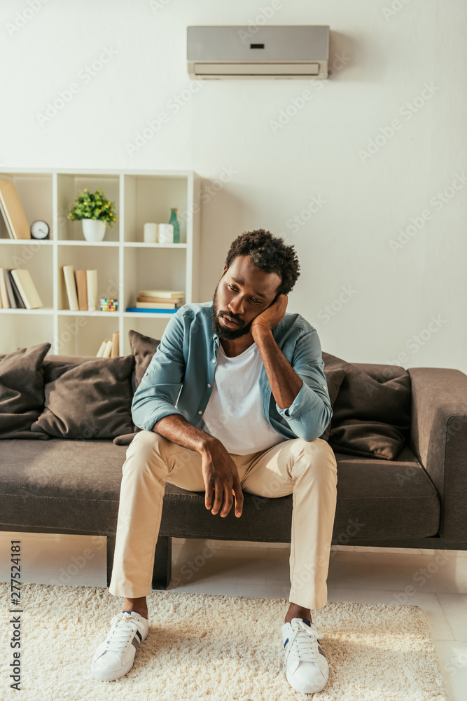 exhausted african american businessman sitting on sofa and suffering from summer heat exhausted african american businessman sitting on sofa and suffering from summer heat