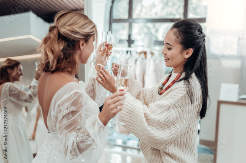 Beautiful bride and her bridesmaid trying a wedding dress.
