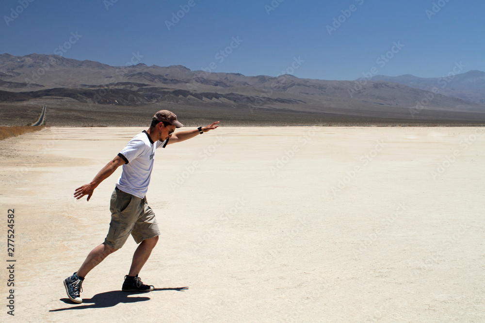 Young man with shorts and sunglasses posing in the desert of Death Valley, California