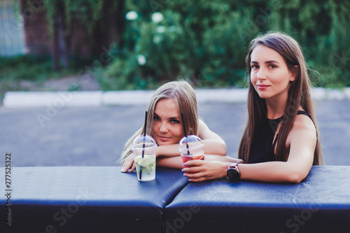 Two pretty girls talking and drinking beverages outdoor