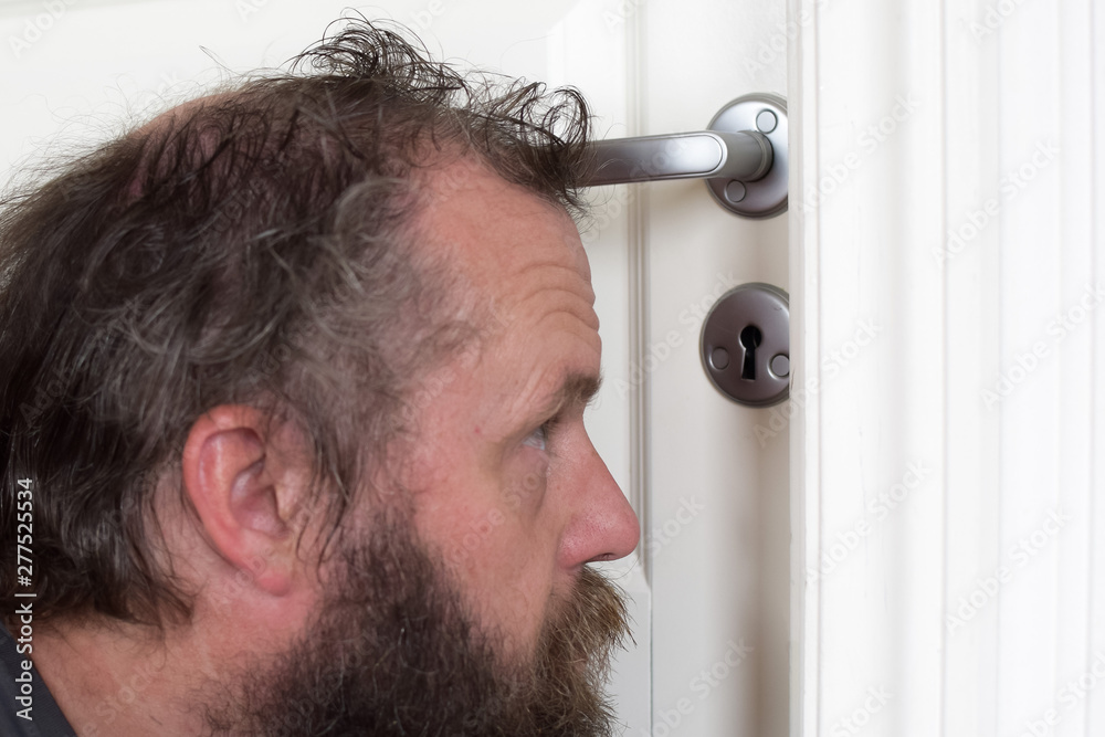 Obraz premium European 50 years old looks into the keyhole. Peeping man. Selective focus