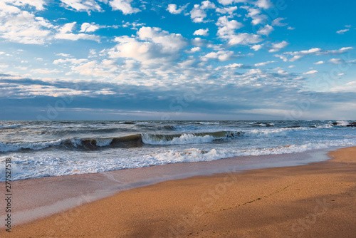 Fototapeta Naklejka Na Ścianę i Meble -  A beach with golden sand, small waves and a beautiful dramatic sky