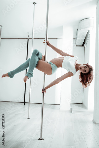 Pole-dancer doing her exercises in empty room.