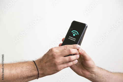 Wallpaper Mural Two hands holding black smart phones while they are wireless charging. Torontodigital.ca