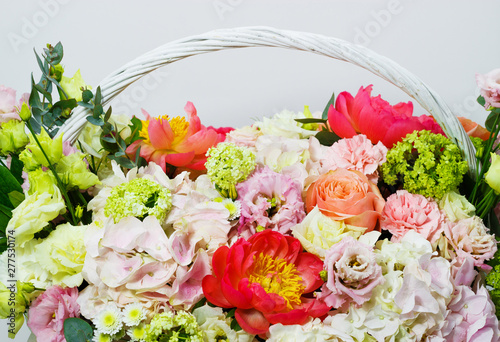 composition with bright colors of peonies  lisianthus  roses in a white basket