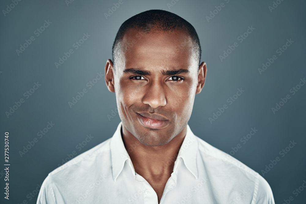So charming. Handsome young African man in shirt looking at camera and smiling while standing against grey background So charming. Handsome young African man in shirt looking at camera and smiling while standing against grey background
