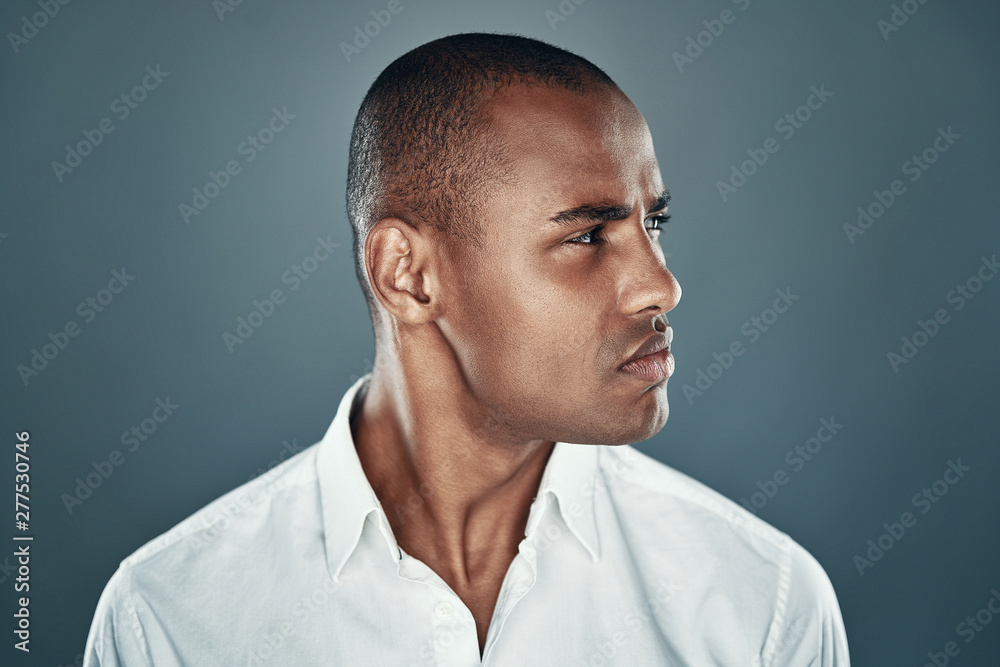 Fototapeta premium Confident look. Handsome young African man in shirt looking away while standing against grey background