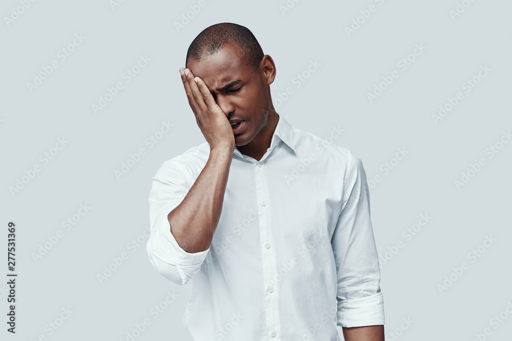 So tired. Young African man making a face while standing against grey background So tired. Young African man making a face while standing against grey background