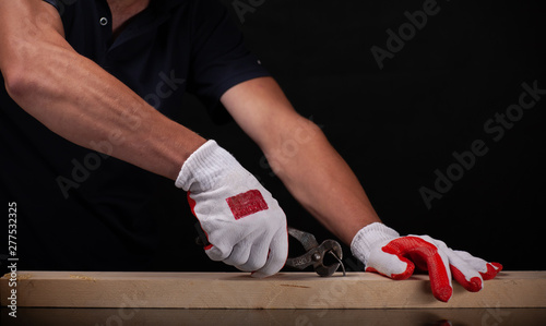 Men's hands use pincers on a black background