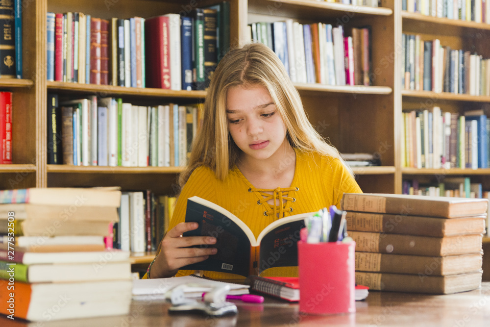 Girl reading book sitting in library Girl reading book sitting in library