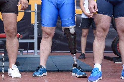 Close-up of an artificial leg of disabled sportsman standing between healthy athletes