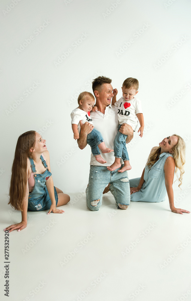 Naklejka premium Young family spending time together and smiling. Parents with young girl and little sons playing and laughting. Family lifestyle. Mother's, father's day, togetherness, parenthood, kid's rights concept