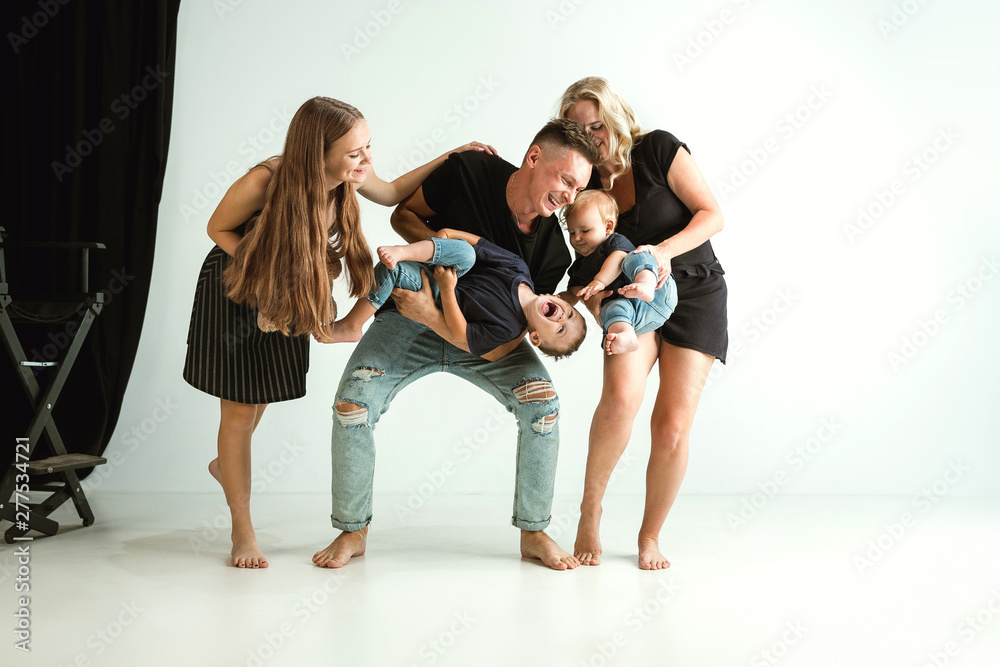 Fototapeta premium Young family spending time together and smiling. Parents with young daughter and little sons playing and laughting. Family lifestyle. Mother's, father's day, togetherness, parenthood, kid's rights