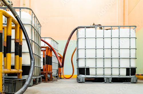 Low view inside of the factory. The large white tanks chemical packaging. Suction pipes for transferring to the main storage tank.