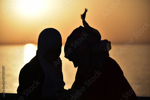 Rear View Of Two Young Women Looking At Sea At Sunset on the sea flom the ship.