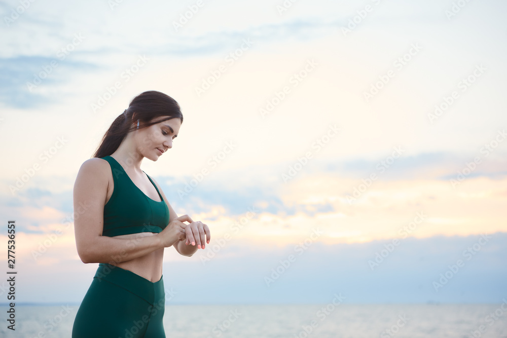 Young brunette woman exercising at the sea shore at sunrise listening to the music. Young brunette woman exercising at the sea shore at sunrise listening to the music.
