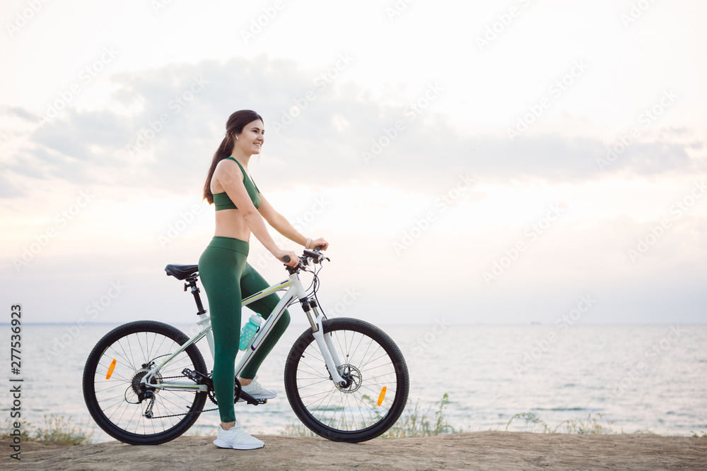 Young brunette woman on a bicycle at sunrise. Young brunette woman on a bicycle at sunrise.