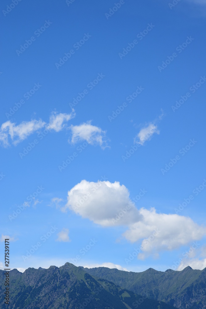 Einzelne weiße Wolken am blauen Himmel über den Alpen Einzelne weiße Wolken am blauen Himmel über den Alpen