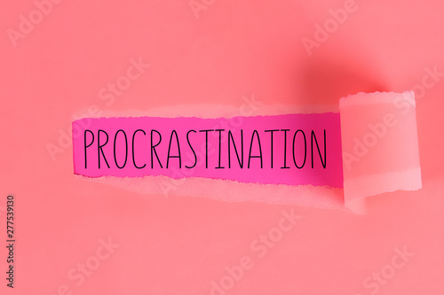 Procrastination, delay, urgency concept. Torn off piece paper opening inscription procrastination. photo