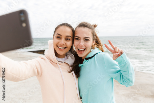 Two happy young fitness women wearing hoodies