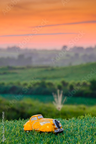 Miniature yellow Car on green grass with beautiful background., Concept for travel around direction to destination with car dealer, cars exhibition show or car insurance for sale customers.