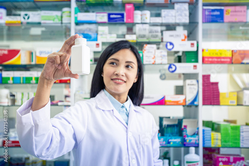 Pharmacist holding medicine bottle in pharmacy. Health care and medical concept.