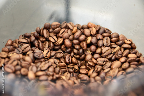 Brown toasted brown beans. Mixture of different roasts and flavors. Type of beans: Cinnamon, Full City, Espresso, Continental, American, Half City... Mild-body coffee. Inside coffee machine container. © mouaad