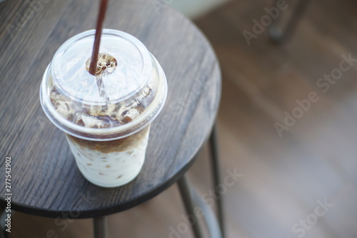 Angle view of No syrup ice Latte on wood chair out side coffee shop.