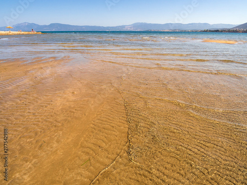 Panoramic views of the sandy beach, the mountains and footprints in the sand at low tide on Liani Ammos beach in Halkida, Greece on a Sunny summer day  the island of Evia photo