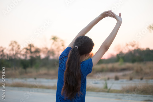 Young women exercise before exercising at the park. She stretched her arms for physical examination with the background of the sun falling.