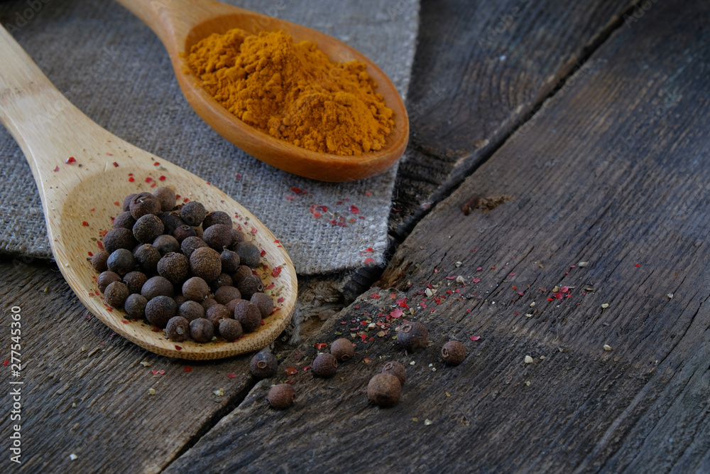 Black pepper and turmeric on a wooden spoon on the background of the old table. Black pepper and turmeric on a wooden spoon on the background of the old table.