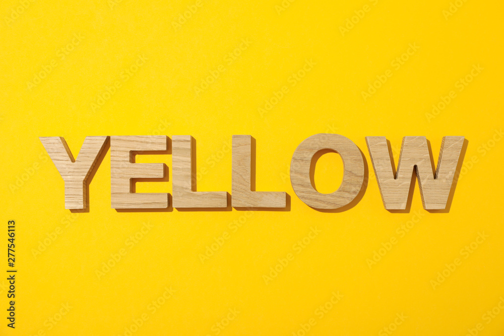Word Yellow laid out in wooden letters on color background Word Yellow laid out in wooden letters on color background